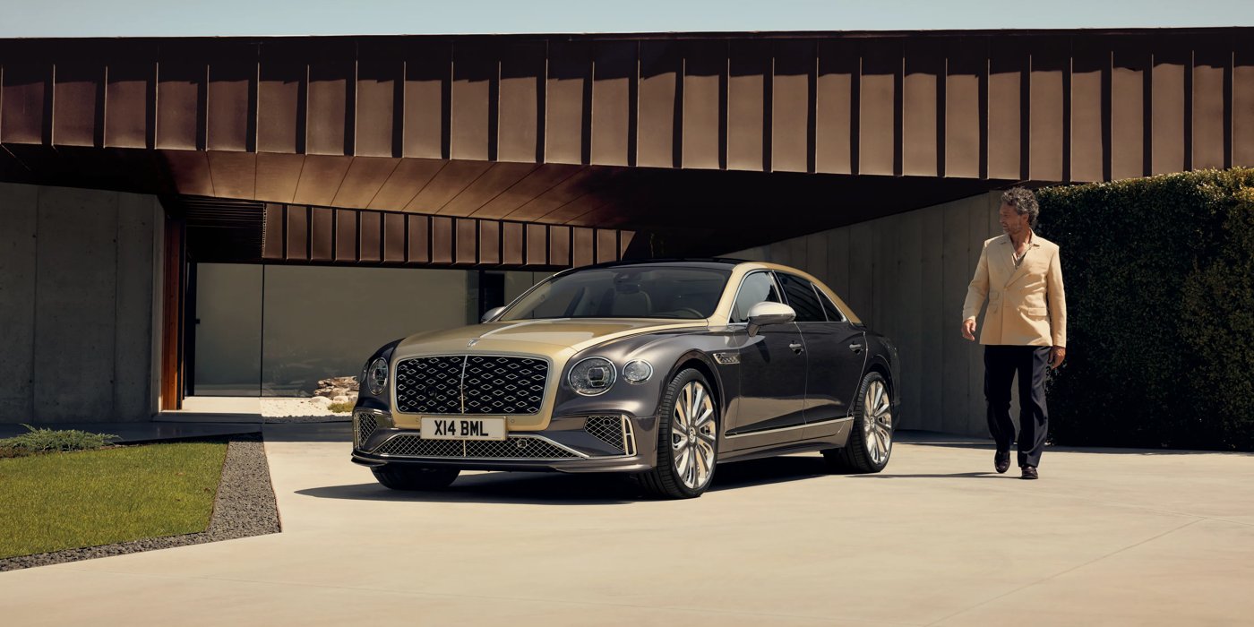 Bentley Jeddah Bentley New Flying Spur Mulliner V8 hybrid sedan front three quarters in Rose Gold over Magnetic paint, parked near modern home