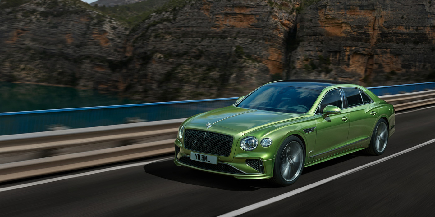 Bentley Jeddah Bentley New Flying Spur Speed v8 hybrid sedan driving dynamically on a mountain road in Tourmaline Green paint