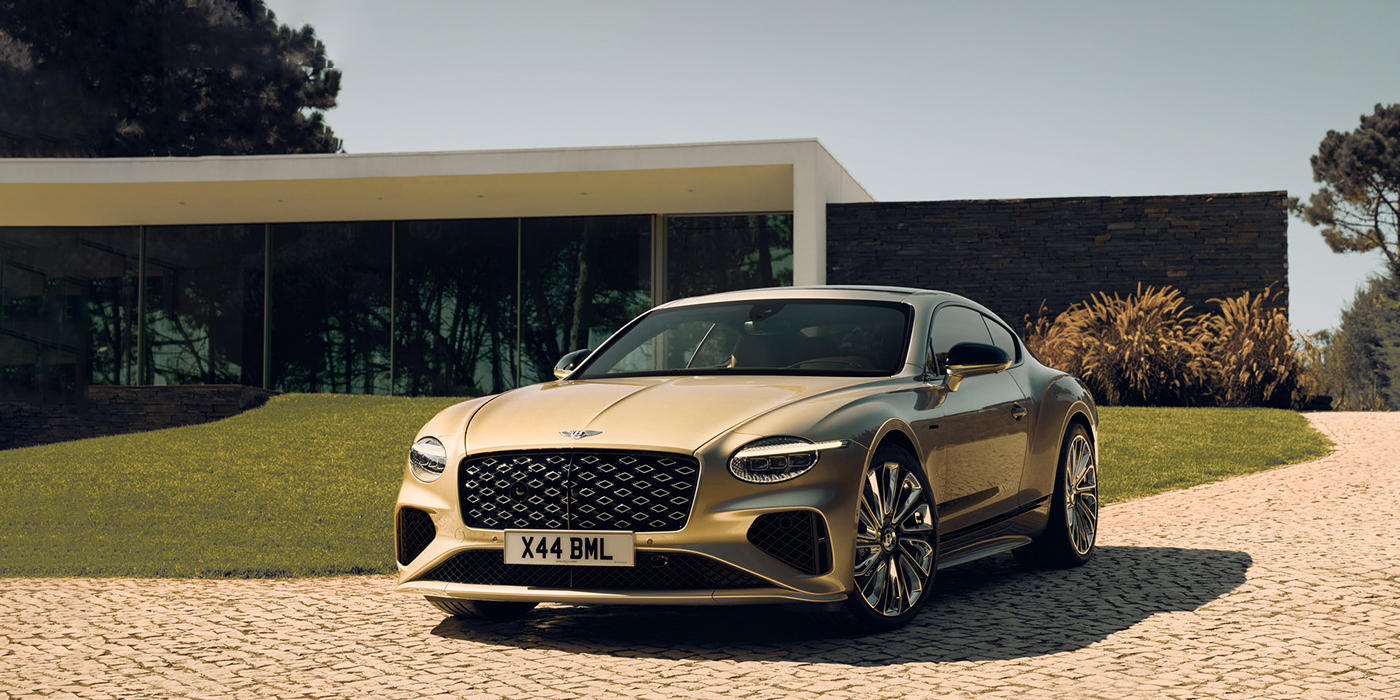 Bentley Jeddah Bentley Continental GT Mulliner coupe front three quarters in Patina paint parked outside a glass fronted building with a grass lawn behind it