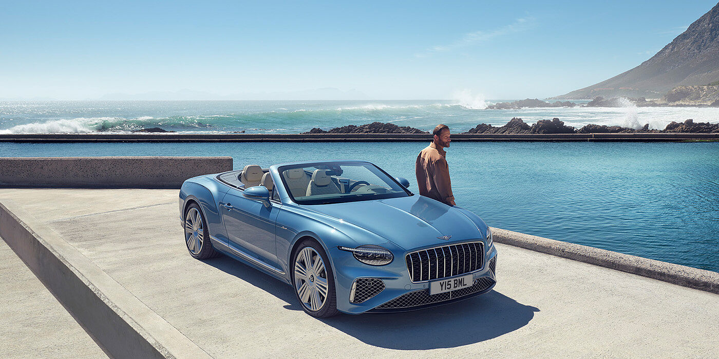 Bentley Jeddah New Bentley Continental GTC Azure convertible front view in Light Windsor blue paint with 22 inch ten spoke wheels parked by the sea in the sunshine
